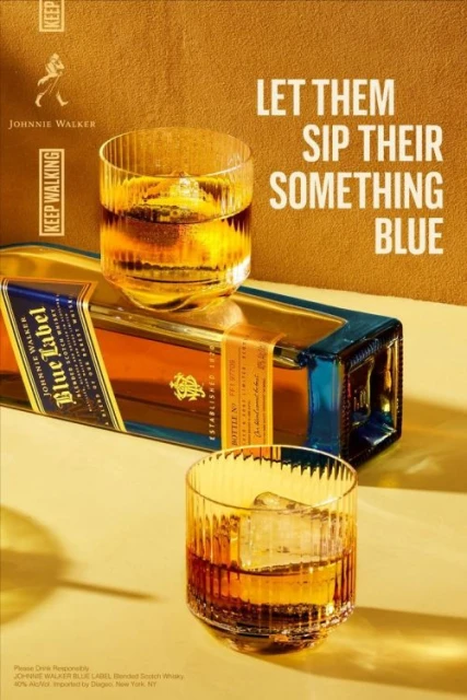 Promotional shot of Johnnie Walker Blue Label whiskey featuring a bottle and two glasses filled with amber liquid.