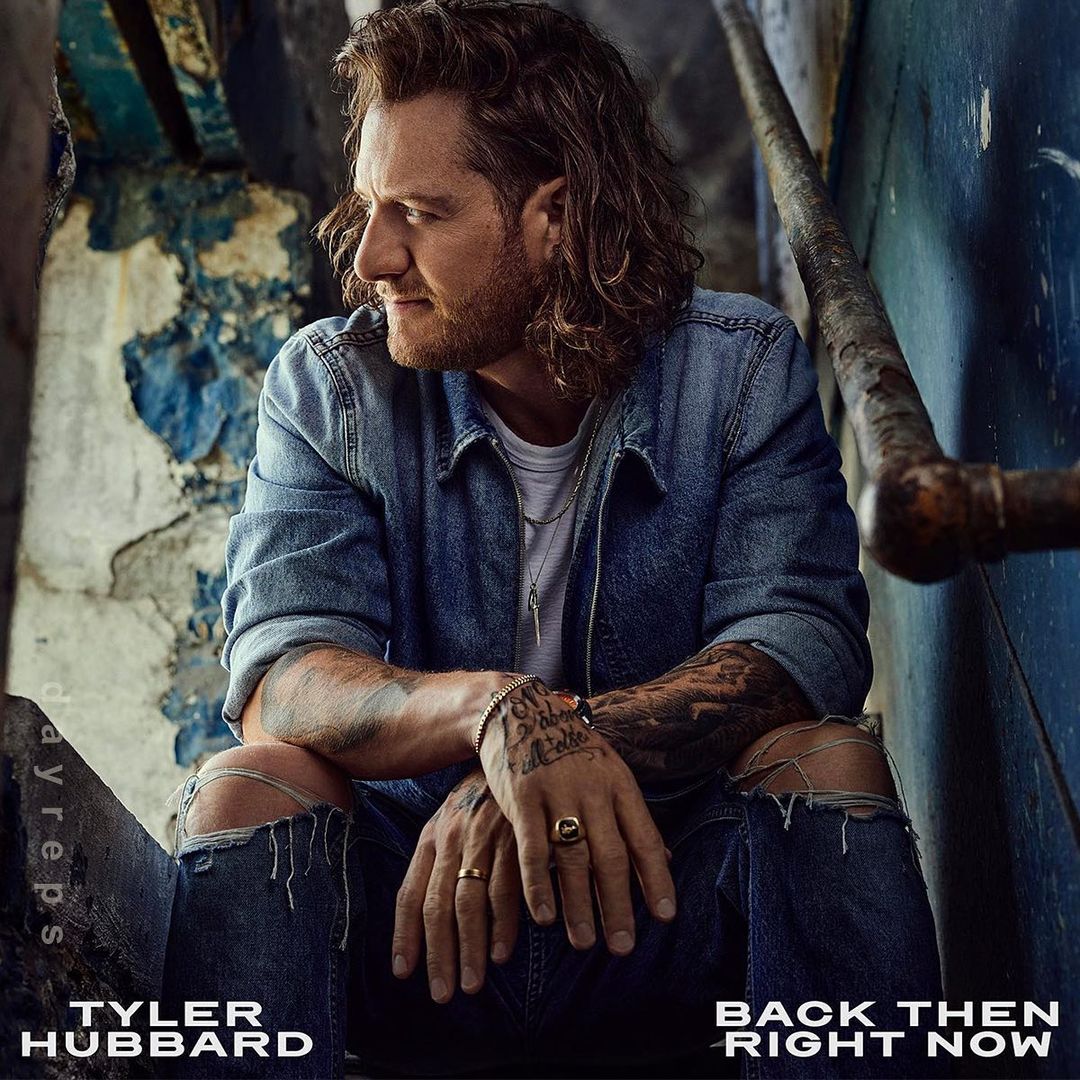 Tyler Hubbard poses in a denim jacket and ripped jeans on concrete stairs, captured in a medium shot with a weathered, urban aesthetic.