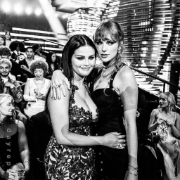Selena Gomez and Taylor Swift embracing at an awards ceremony photographed by John Shearer in a black and white portrait.