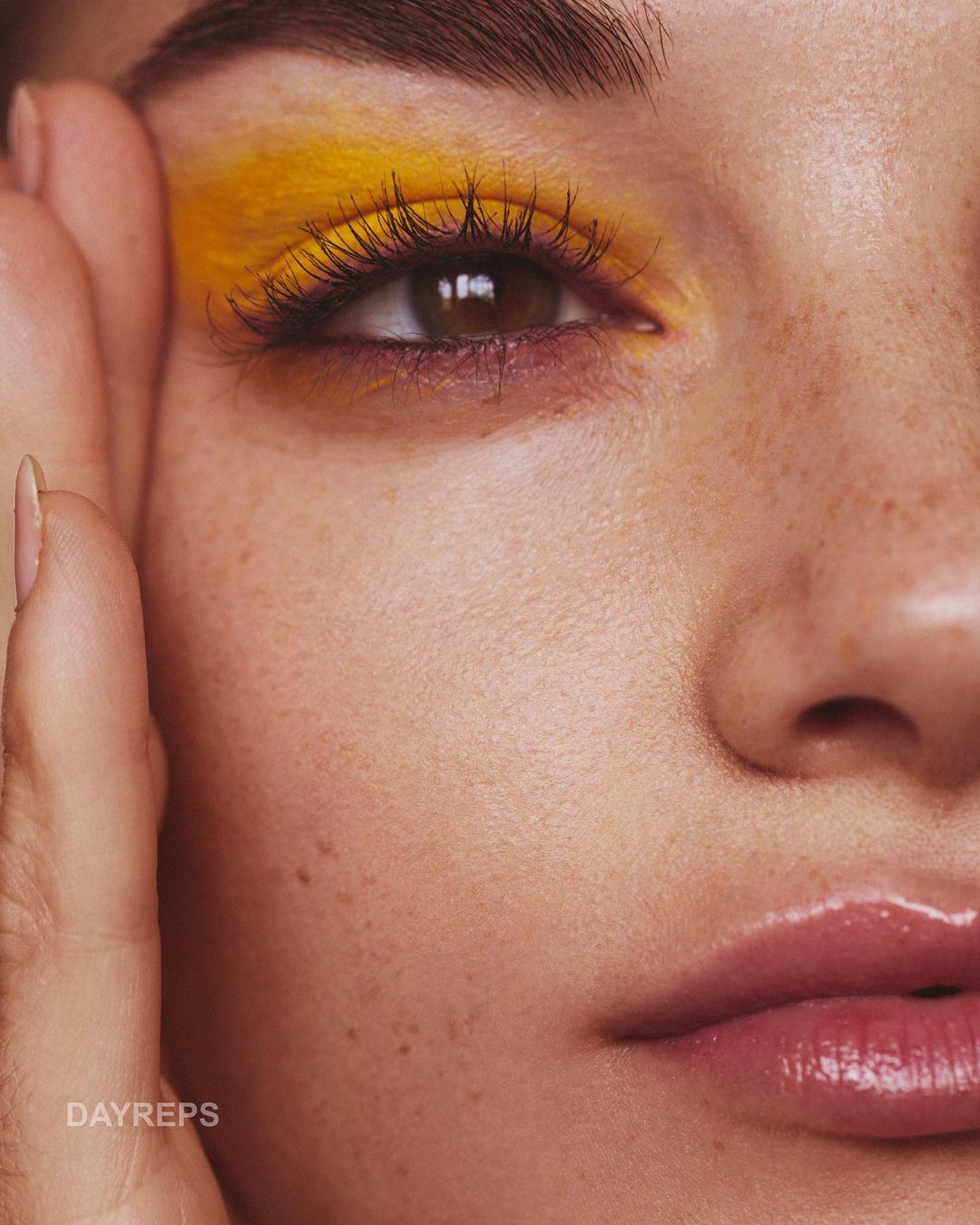 Close-up of a woman's face with bright yellow eyeshadow and glossy lips, focusing on beauty and cosmetic style. Perfect for beauty ads.