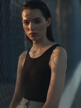 Portrait of a woman wearing a black tank top with chain-link fence shadows cast across her face and body by photographer Gray Hamner.