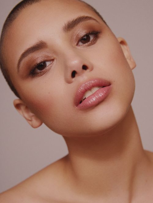 Close-up of an adult female with short hair and neutral expression. The woman is wearing makeup in a studio setting.