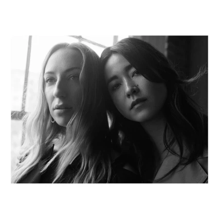 Black and white portrait of two women posing close together in front of a window by photographer Gray Hamner
