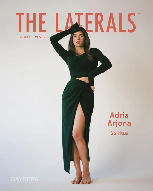 Adria Arjona poses in a long-sleeved dark green crop top and matching skirt with a slit, set against a pale peach backdrop for a cover shoot.