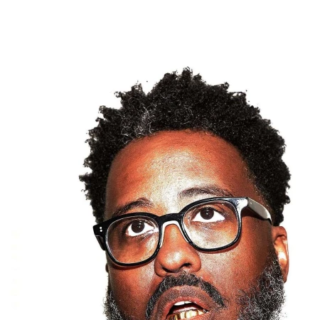 Close-up portrait of a Black man wearing black frame glasses and looking upward against a bright white background