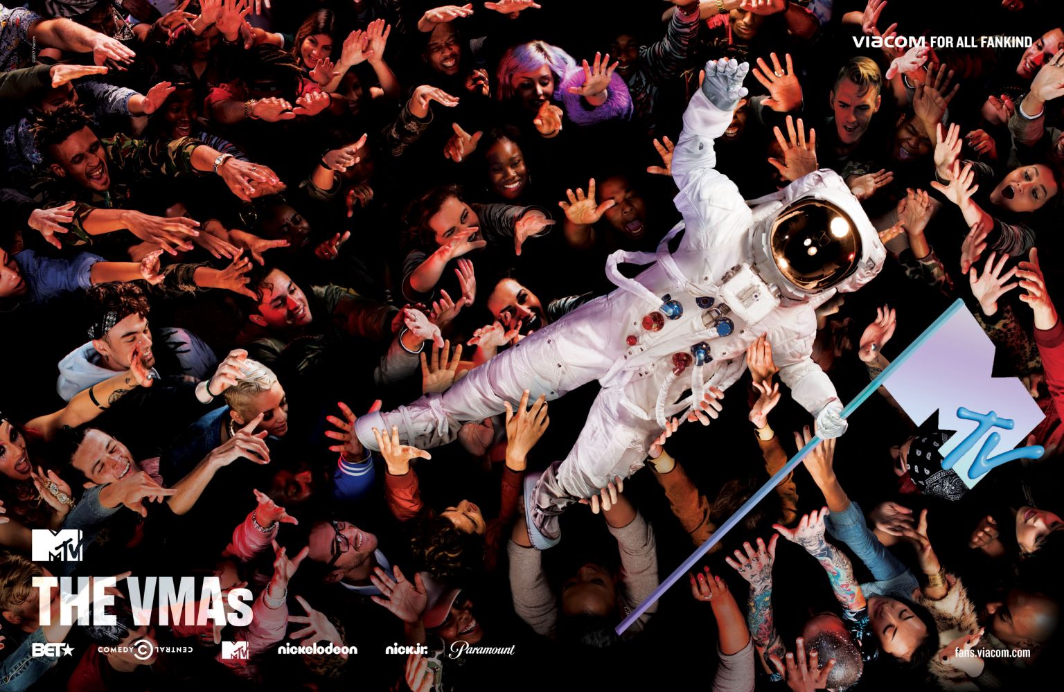 An astronaut is crowd surfing in a large crowd of people with the MTV logo and brand logos in the foreground and background.