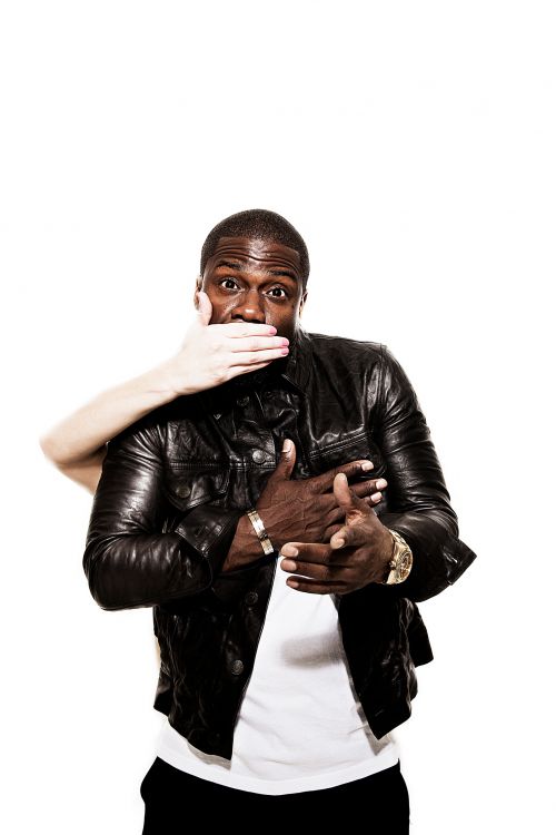 Close-up studio shot of an African-American male with a surprised expression, and a hand covering his mouth wearing a black leather jacket.