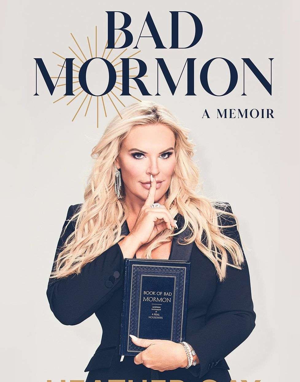 Book cover featuring a blonde woman in a black blazer, holding her memoir, titled 'Bad Mormon', against a neutral backdrop.