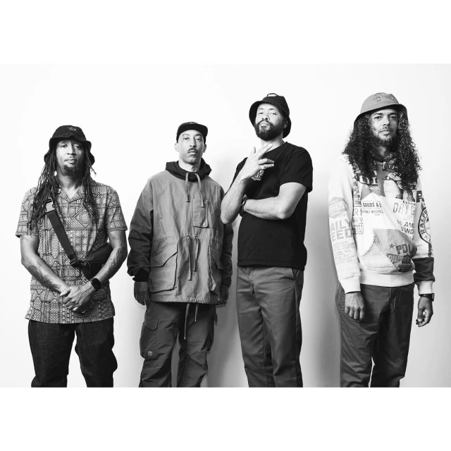 Group of four adult males in casual outfits pose against a white backdrop; various hats, jackets, and t-shirts create a streetwear aesthetic.