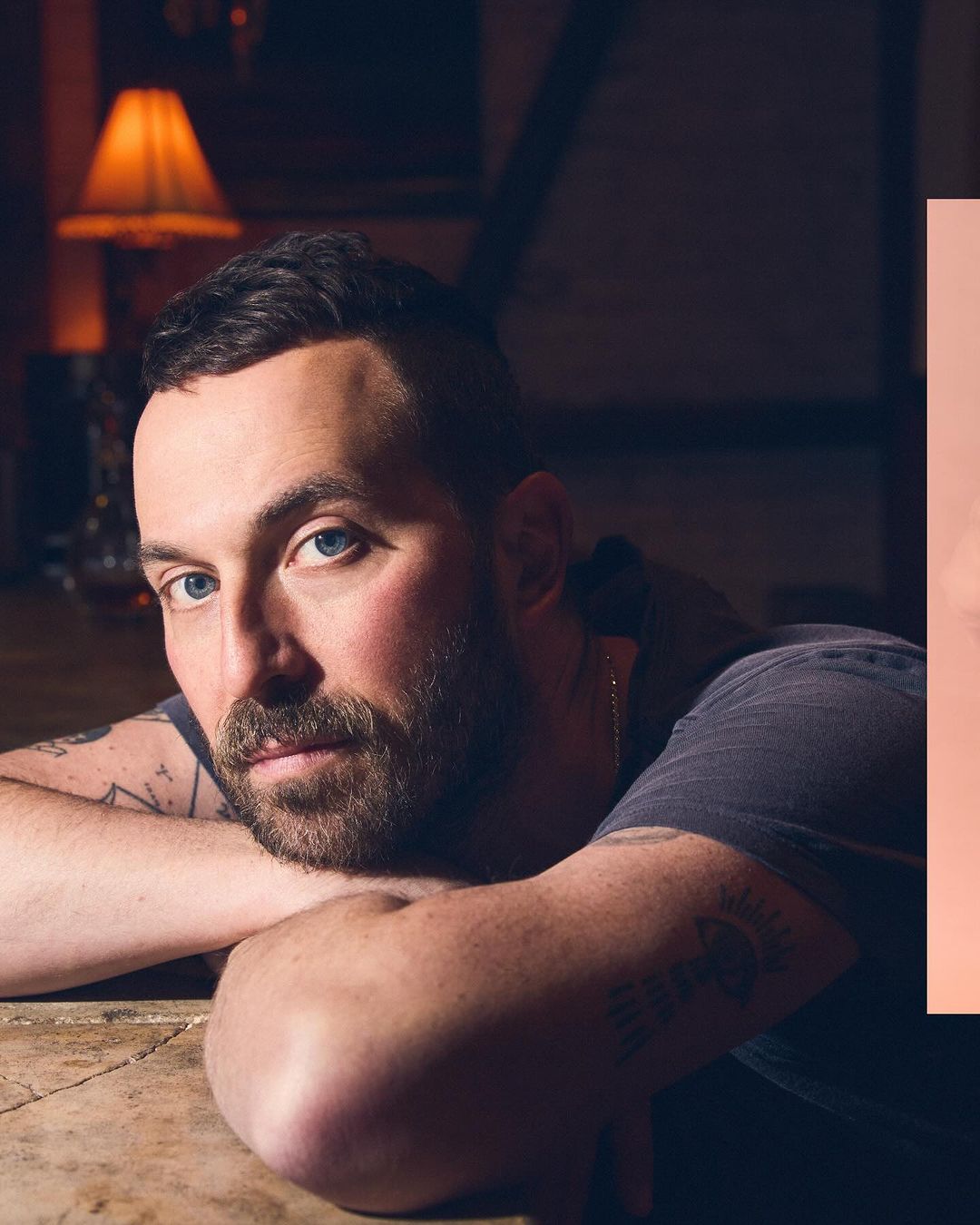 Portrait of a man with short brown hair, beard, and blue eyes resting his chin on his arms, photographed by Koury Angelo.
