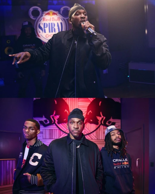 Performance shot featuring a singer with a microphone, backed by two men and brand logos for Red Bull and Oracle in a casual indoor setting.