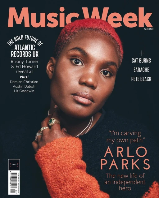 Music Week magazine cover featuring Arlo Parks. Close-up of Arlo Parks with coral hair wearing an orange sweater and jewelry against a dark background.