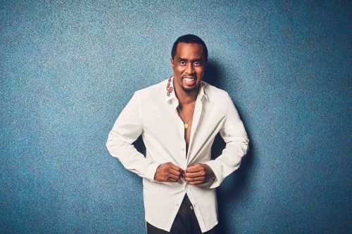 Portrait of a smiling adult male in a white shirt, against a blue textured background, looking at the camera.