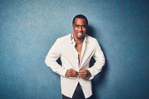 Portrait of a smiling adult male in a white shirt, against a blue textured background, looking at the camera.