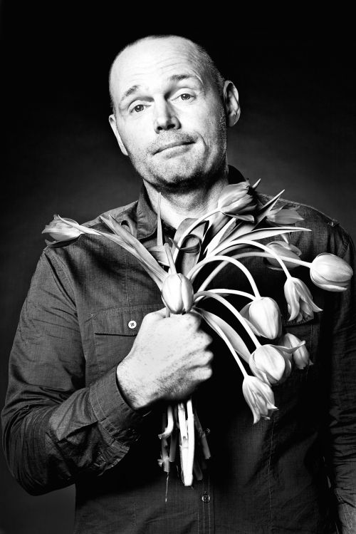 Portrait of a bald man holding a bouquet of tulips, photographed in monochrome by Koury Angelo.