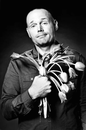 Portrait of a bald man holding a bouquet of tulips, photographed in monochrome by Koury Angelo.