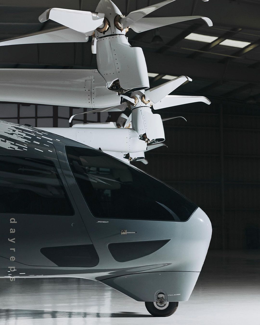 Futuristic VTOL aircraft with gray body and white rotors, showcasing modern aviation design in an indoor setting.