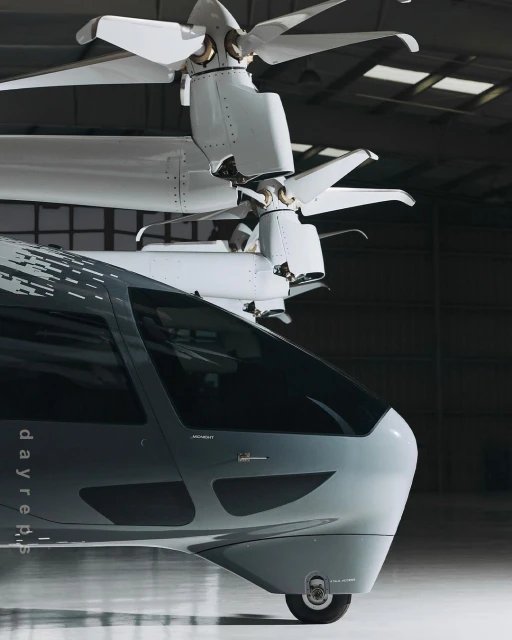 Futuristic VTOL aircraft with gray body and white rotors, showcasing modern aviation design in an indoor setting.