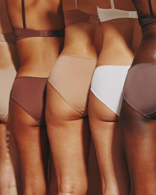 Partial view of five diverse women in matching bra and panty sets posing in a row against a neutral backdrop in a studio setting.