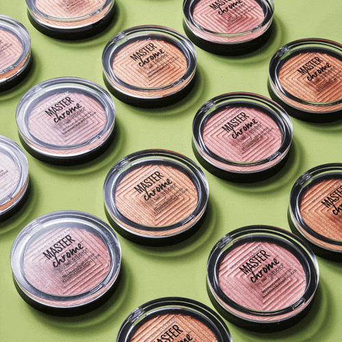 Close-up of multiple makeup compacts with a clear lid on a green background; beauty product advertisement; studio lighting.