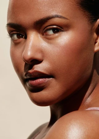 Close-up portrait of a black woman with a glowing complexion and natural makeup looking away from the camera in Los Angeles.