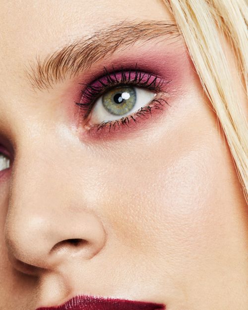 Close-up beauty portrait focusing on a woman eye with purple eyeshadow and dark mascara by photographer Katie Thompson.