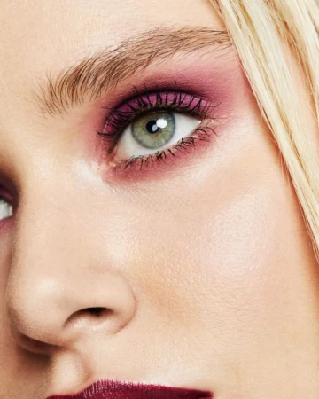 Close-up beauty portrait focusing on a woman eye with purple eyeshadow and dark mascara by photographer Katie Thompson.