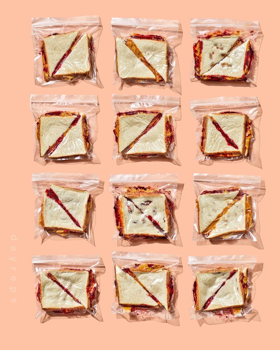 Eleven sealed plastic bags, each containing a diagonally-cut sandwich, arranged in rows against a light peach-colored background. Food photography.