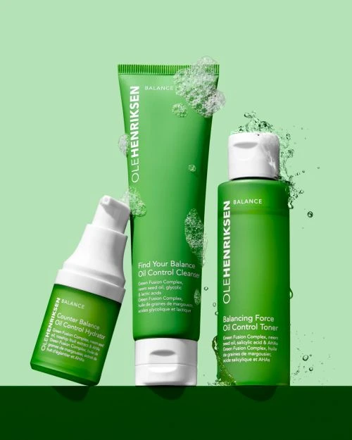 Three green and white Olehenriksen Balance skincare products consisting of a cleanser, toner, and moisturizer sit on a gradient backdrop.