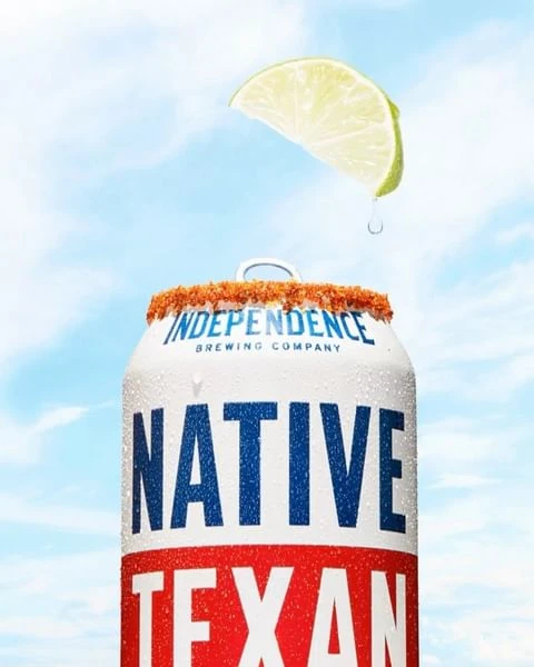 Refreshing beer can with a slice of lime against a cloudy sky, ideal for summer refreshment and beverage promotions.