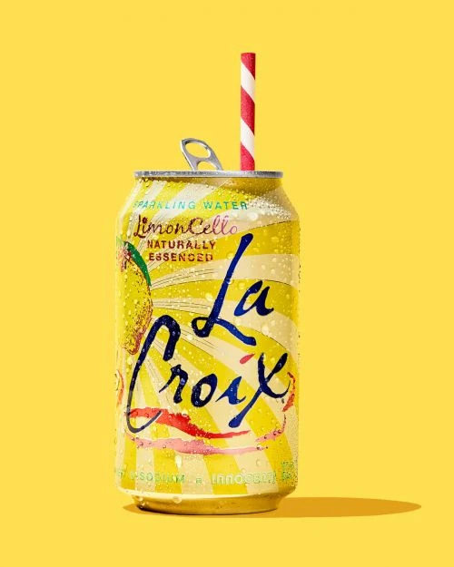 La Croix LimonCello can with red and white striped straw against a solid yellow background in a studio setting.
