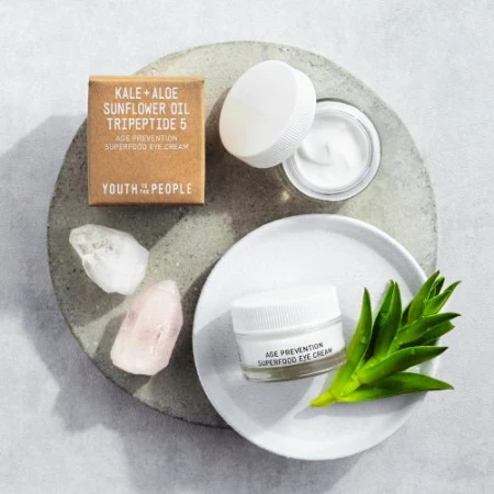 Promotional tabletop product shot featuring Youth to the People skincare products including an eye cream and product box on a stone surface.