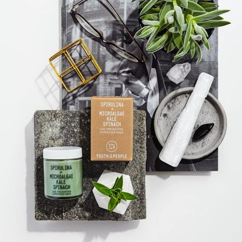 Still life product photography featuring Youth To The People skincare, succulents, crystals, and glasses on a white surface.