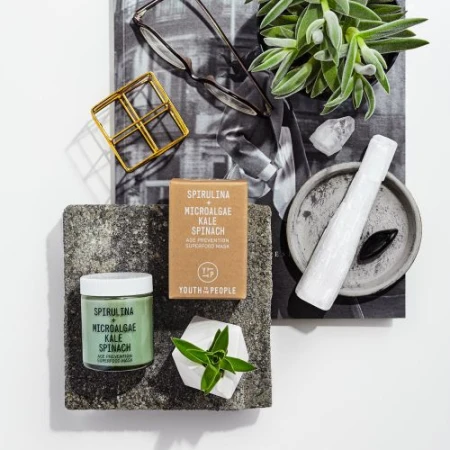 Still life product photography featuring Youth To The People skincare, succulents, crystals, and glasses on a white surface.