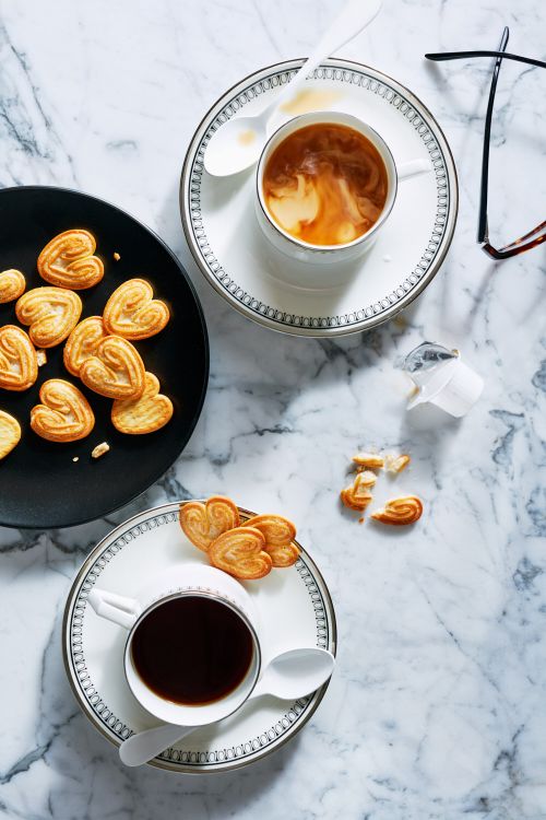 Overhead shot of two cups of coffee with heart-shaped cookies on a marble surface, creating a cozy and inviting breakfast scene.