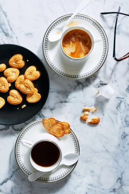 Overhead shot of two cups of coffee with heart-shaped cookies on a marble surface, creating a cozy and inviting breakfast scene.