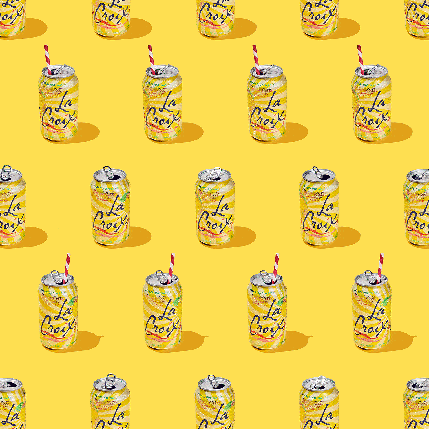 Sparkling water cans arranged in a repeating pattern on a bright yellow background, some with striped straws, under studio lighting.