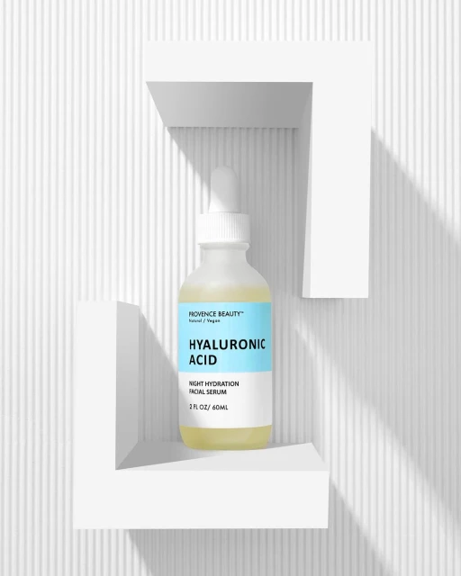 Hyaluronic acid serum in a clear bottle with a dropper, displayed on a white corner shelf against a ridged white background. 