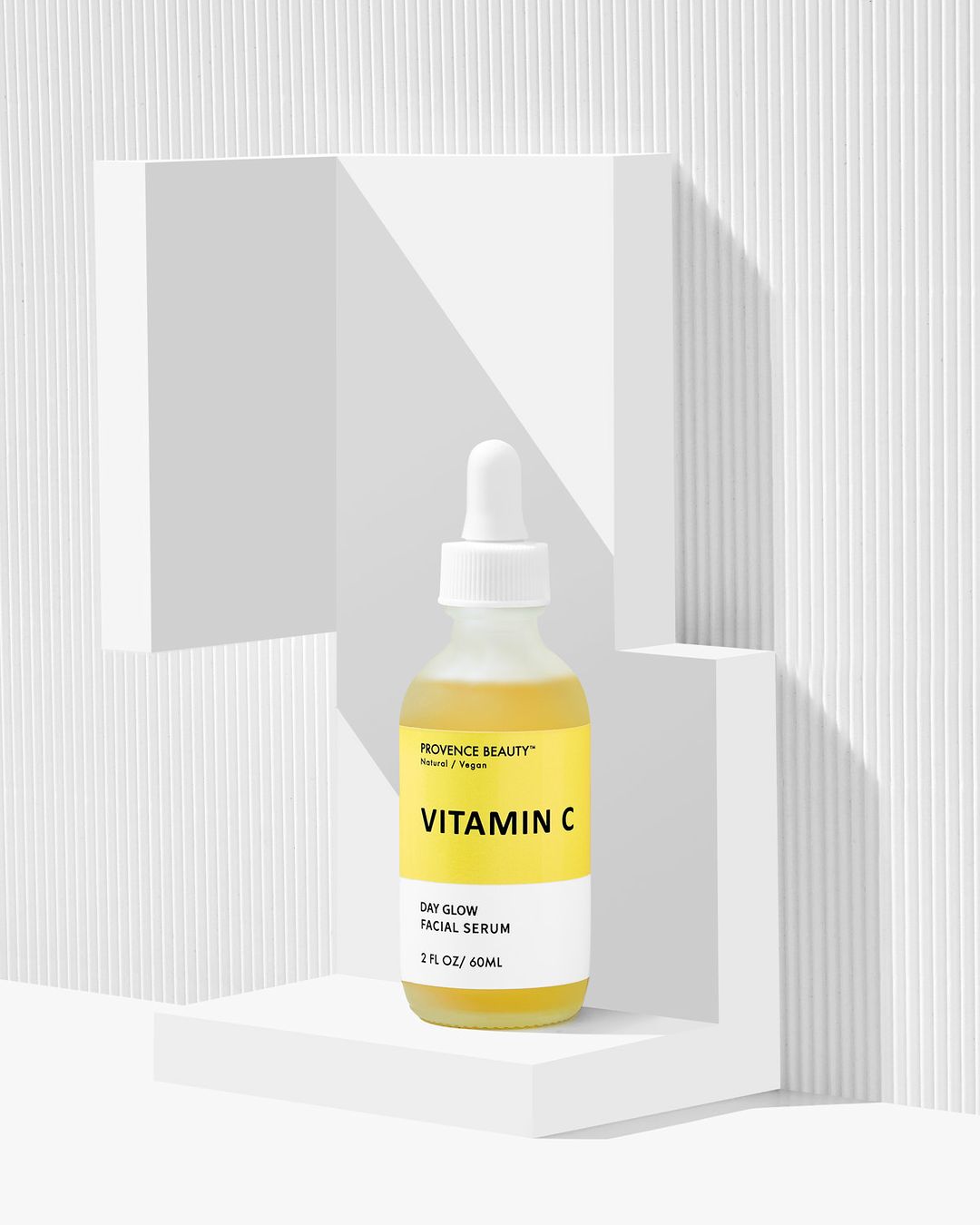 Vitamin C facial serum in a bottle, displayed on a white geometric platform against a textured white background, beauty and skincare.