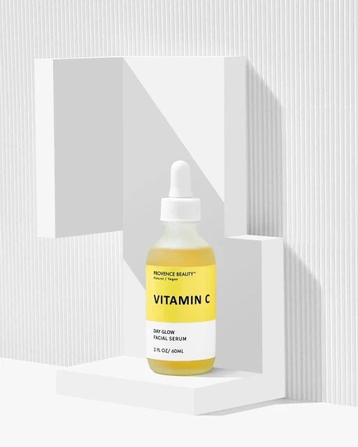 Vitamin C facial serum in a bottle, displayed on a white geometric platform against a textured white background, beauty and skincare.