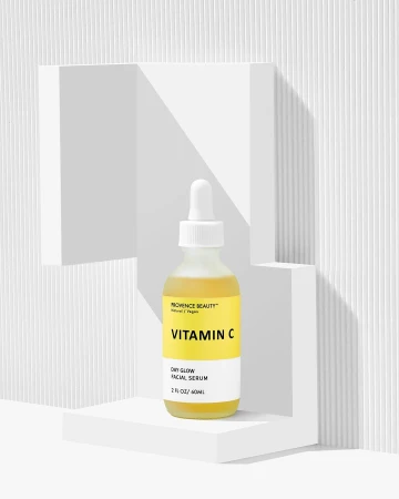 Vitamin C facial serum in a bottle, displayed on a white geometric platform against a textured white background, beauty and skincare.