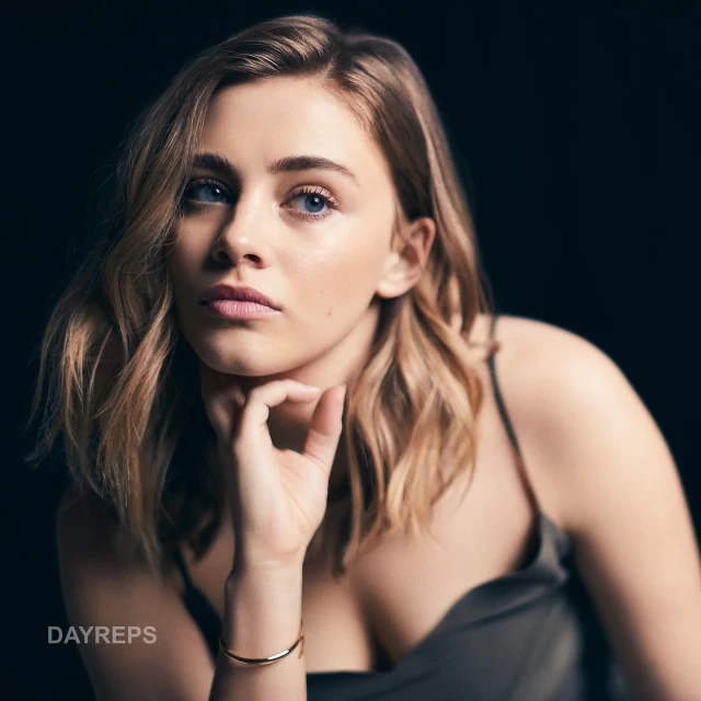 Portrait of an adult woman with blonde hair in a studio setting, wearing a silky top and a bracelet, looking off into the distance.