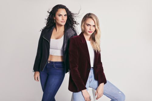 Two women pose in jeans and jackets against a white backdrop. One wears a black leather jacket; the other, a maroon velvet blazer.