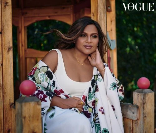 Portrait of Mindy Kaling wearing a floral-print shawl in a wood structure, set against a green foliage background with Vogue logo.
