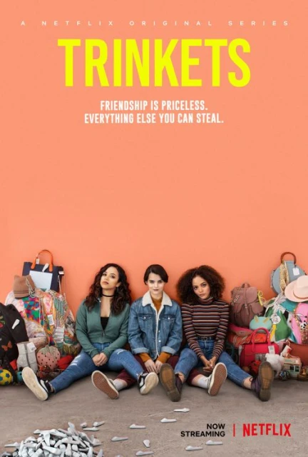 Promotional poster for Netflix series 'Trinkets' with three teenage women seated on the floor against a peach wall surrounded by bags.