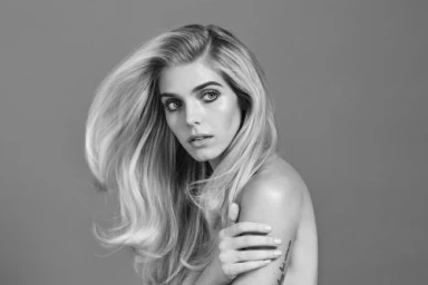 Monochrome portrait of a woman with long sweeping blonde hair looking back over her shoulder.