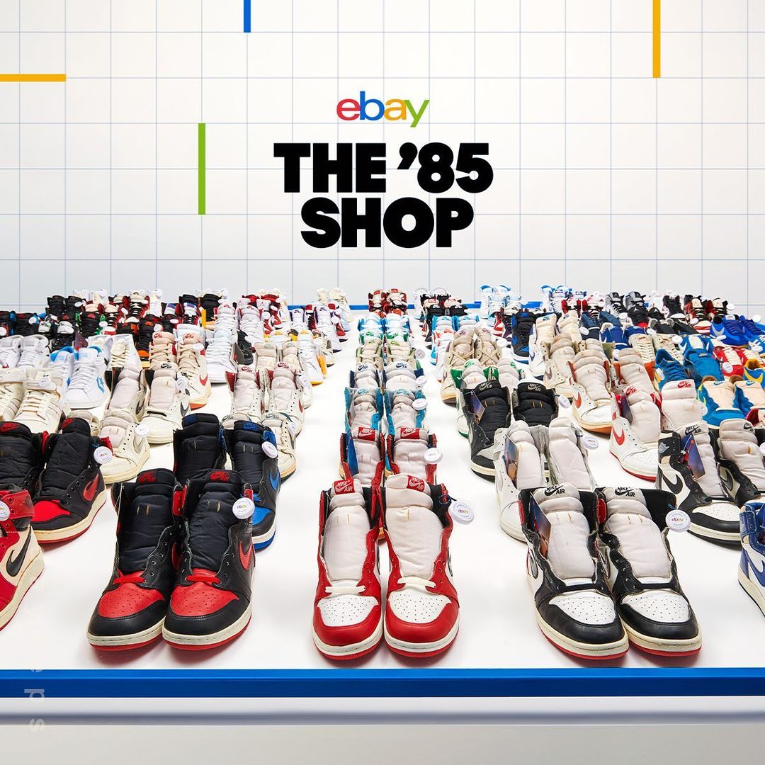Numerous pairs of athletic shoes are displayed on a white surface in a grid pattern, with eBay and 'The 85 Shop' text visible above.