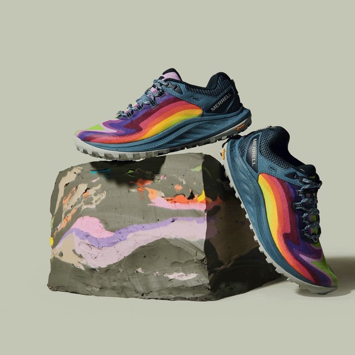 Pair of Merrell running shoes displayed on a textured block against a light gray backdrop in a studio product shot.