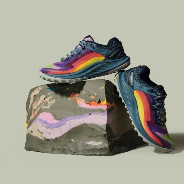 Pair of Merrell running shoes displayed on a textured block against a light gray backdrop in a studio product shot.