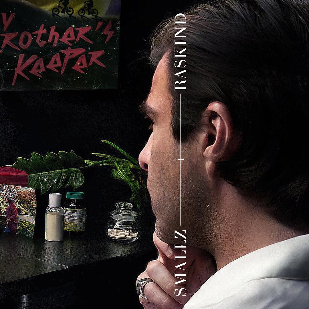 Side profile portrait of a thoughtful adult male next to bottles, plants, and a framed photograph, against a dark background.